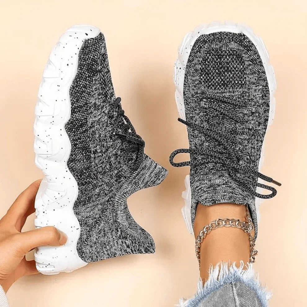 Dark grey knit lace-up sneakers with white sole, side view with ankle chain