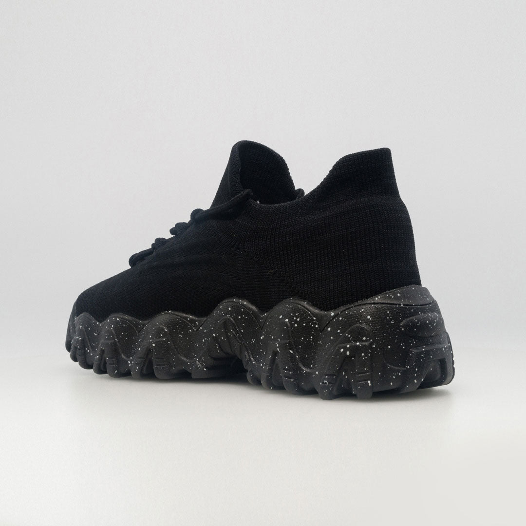 Black orthopedic sneaker from side-back angle with lace-up upper and speckled tread