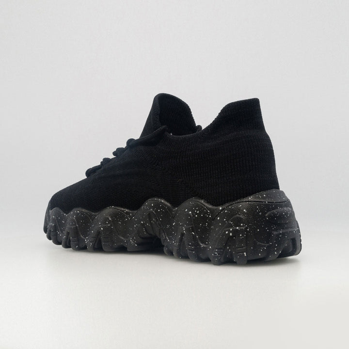 Black orthopedic sneaker from side-back angle with lace-up upper and speckled tread